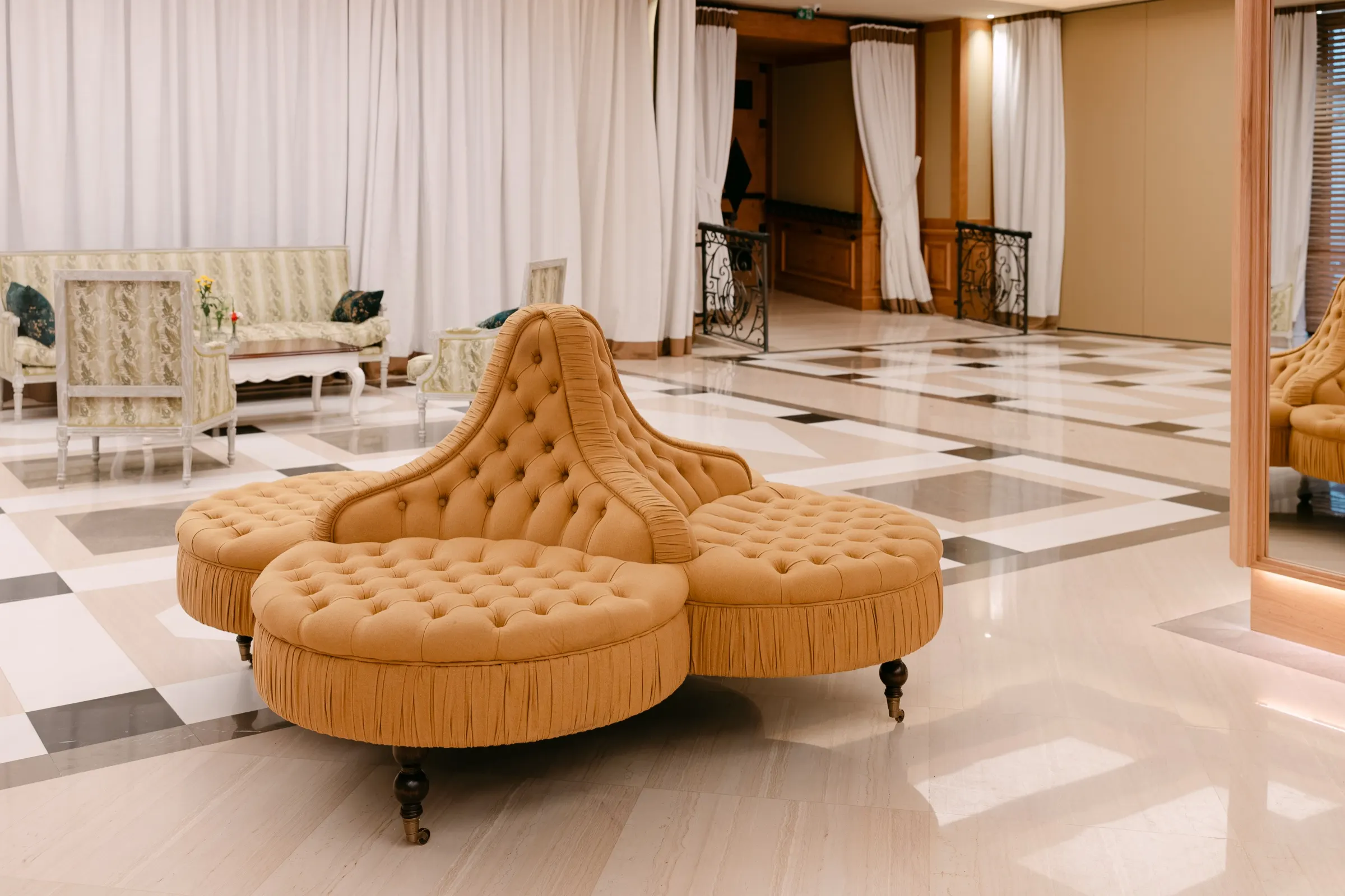 Sofá capitoné dorado en un salón con suelo de mármol del Hotel Majestic durante el Condé Nast Summit. Fotografía de Noomadik.