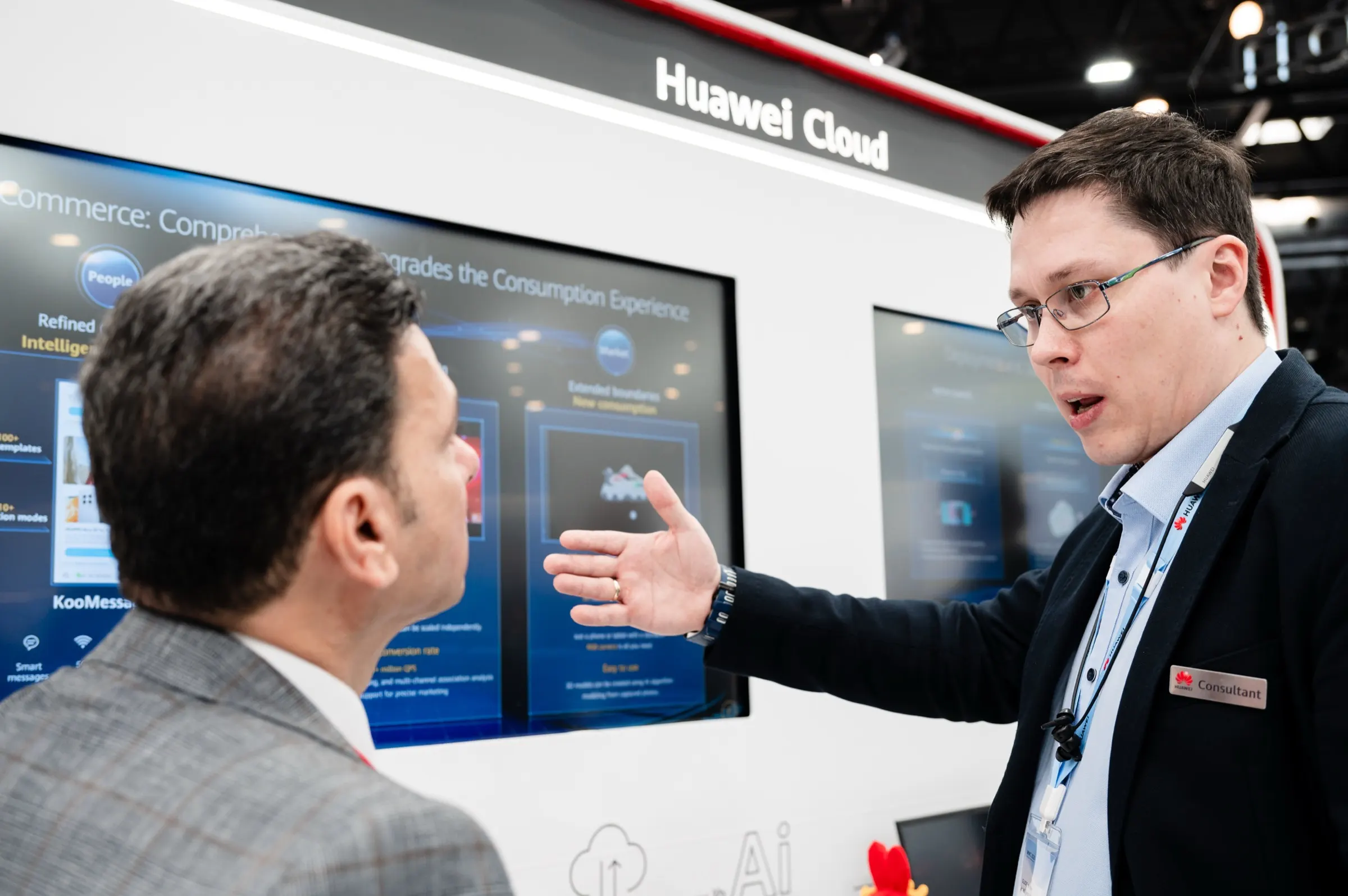 Consultor de Huawei Cloud explicando una demostración en pantalla a un visitante del stand en el MWC Barcelona. Fotografía de Noomadik.