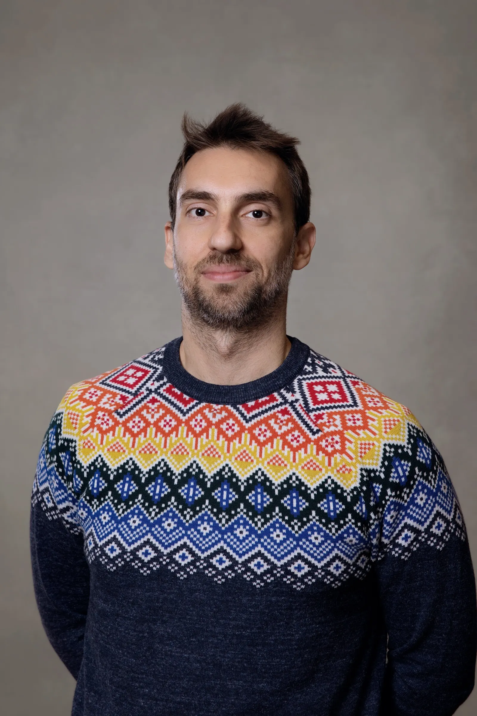 Retrato corporativo de un hombre con jersey estampado sobre fondo gris en el retiro de Digital Science. Fotografía de Noomadik.