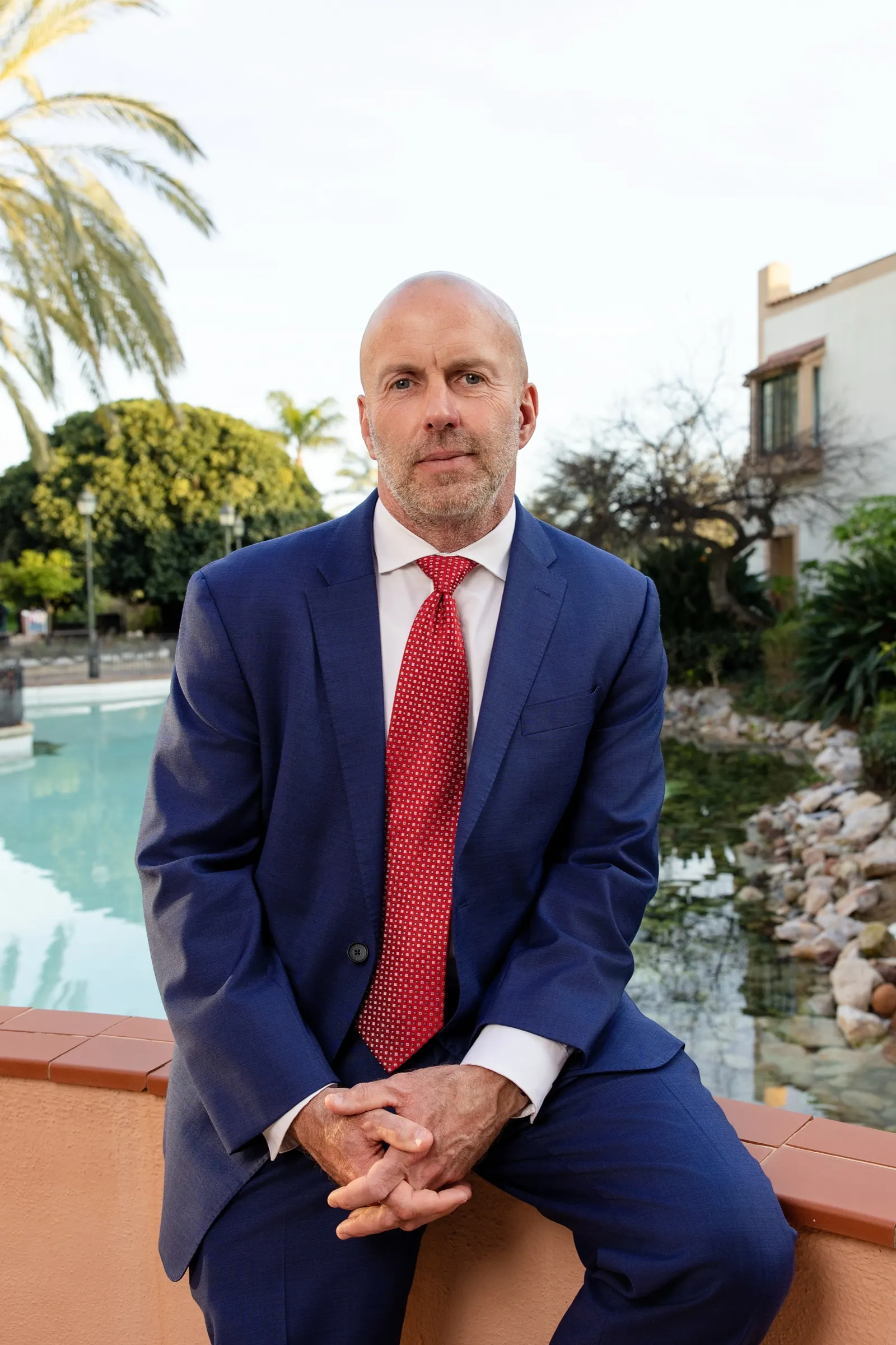 Retrato en exterior de un directivo con traje azul sentado junto a un estanque en PortAventura. Fotografía de Noomadik.