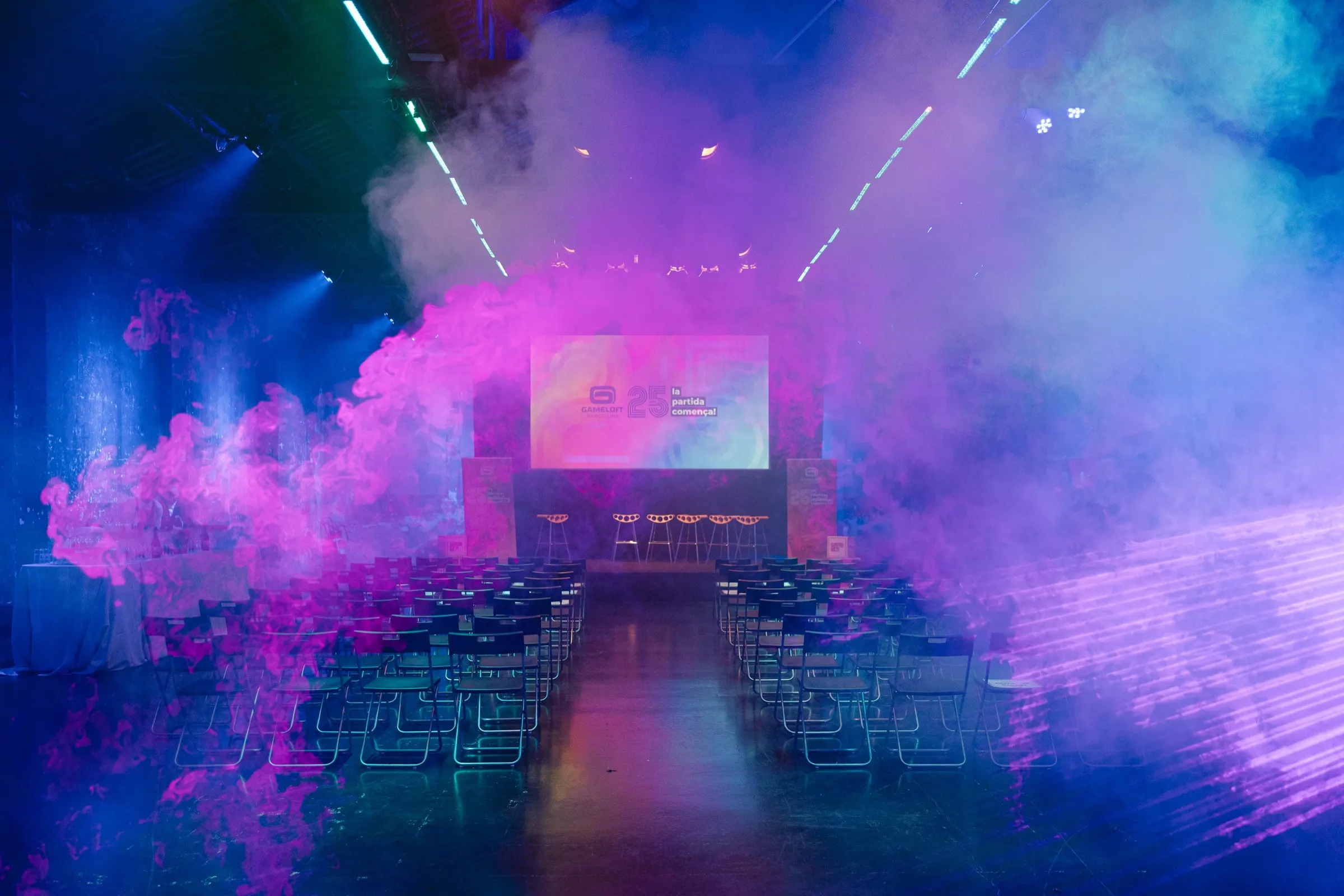 Sala de charlas con humo y luces de colores antes del 25 aniversario de Gameloft Barcelona. Fotografía de Noomadik.