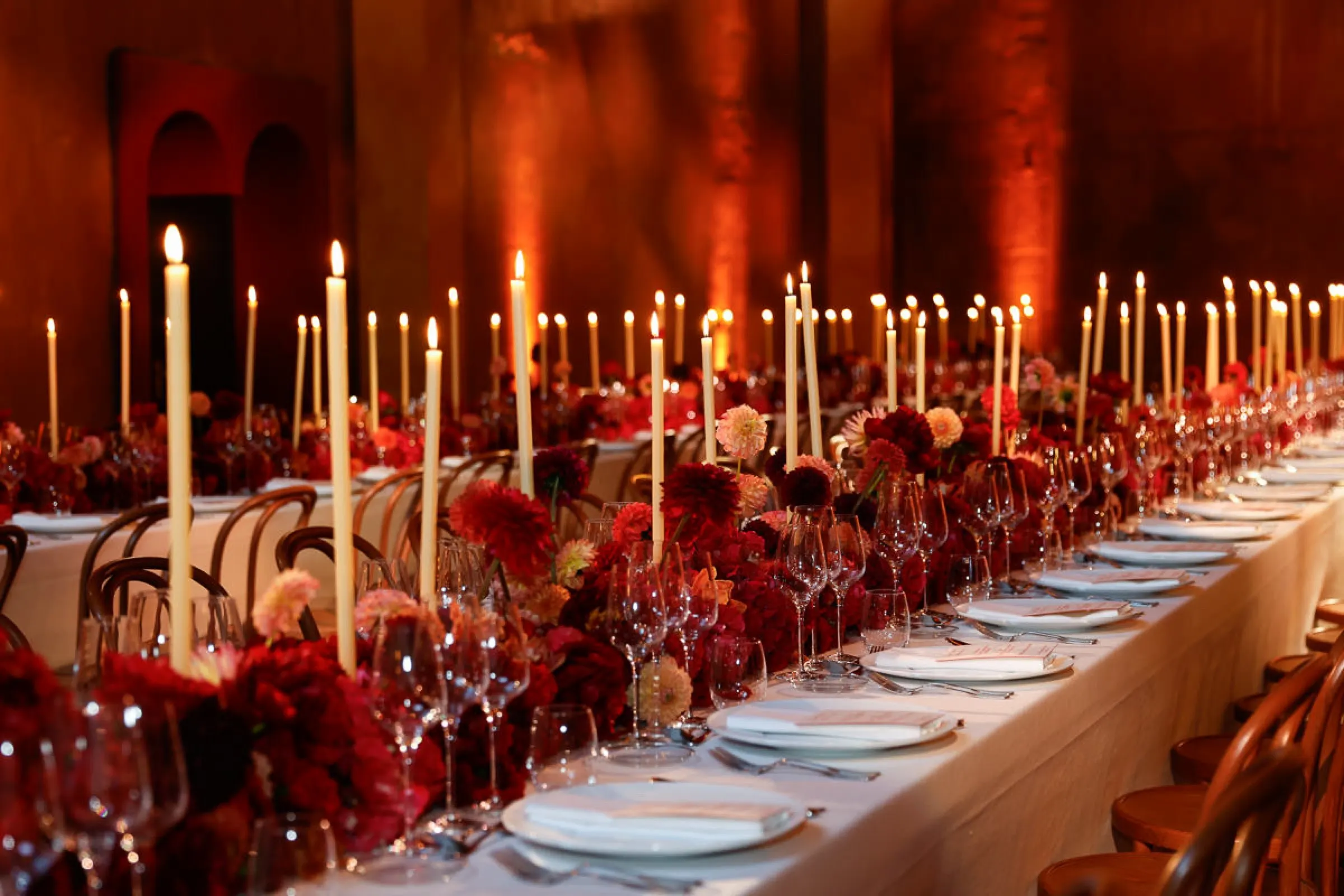 Mesa de gala con velas altas y flores rojas para la colección Cruise de Louis Vuitton. Fotografía de Noomadik.