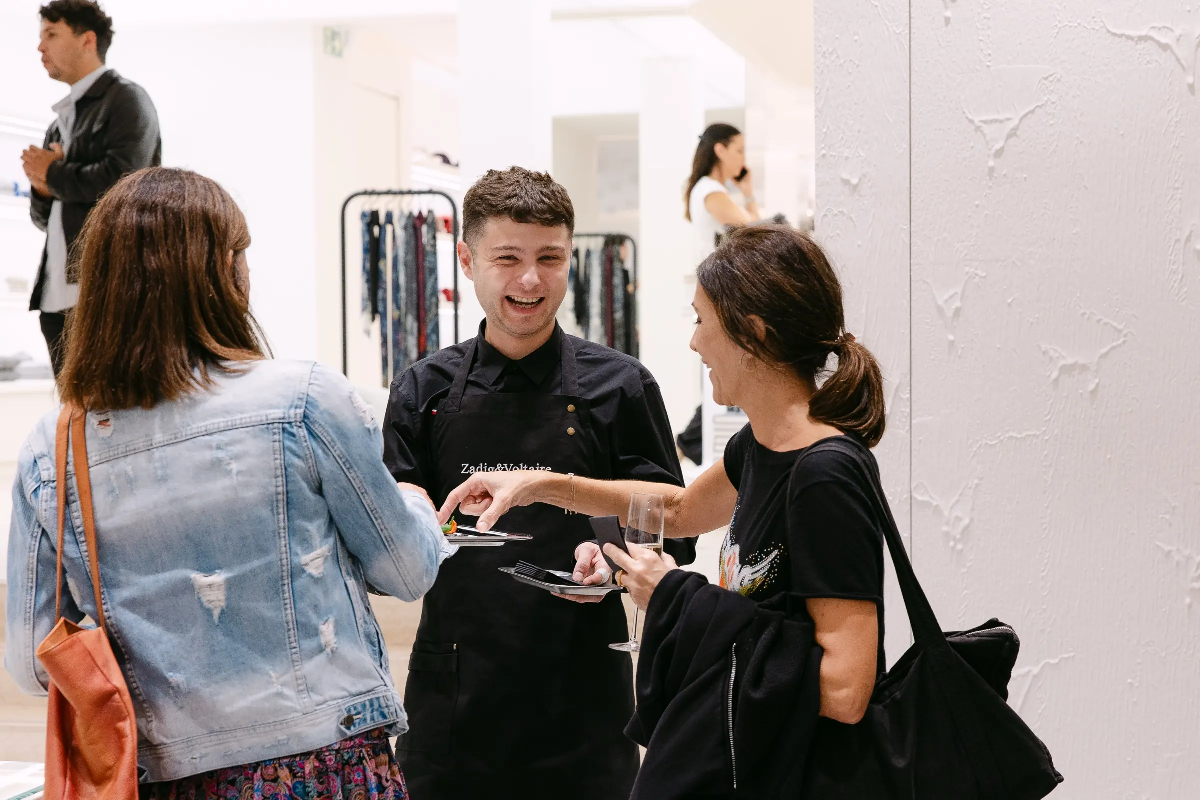 Dependiente atendiendo a dos invitadas con cava en la tienda de Zadig & Voltaire en Barcelona. Fotografía de Noomadik.