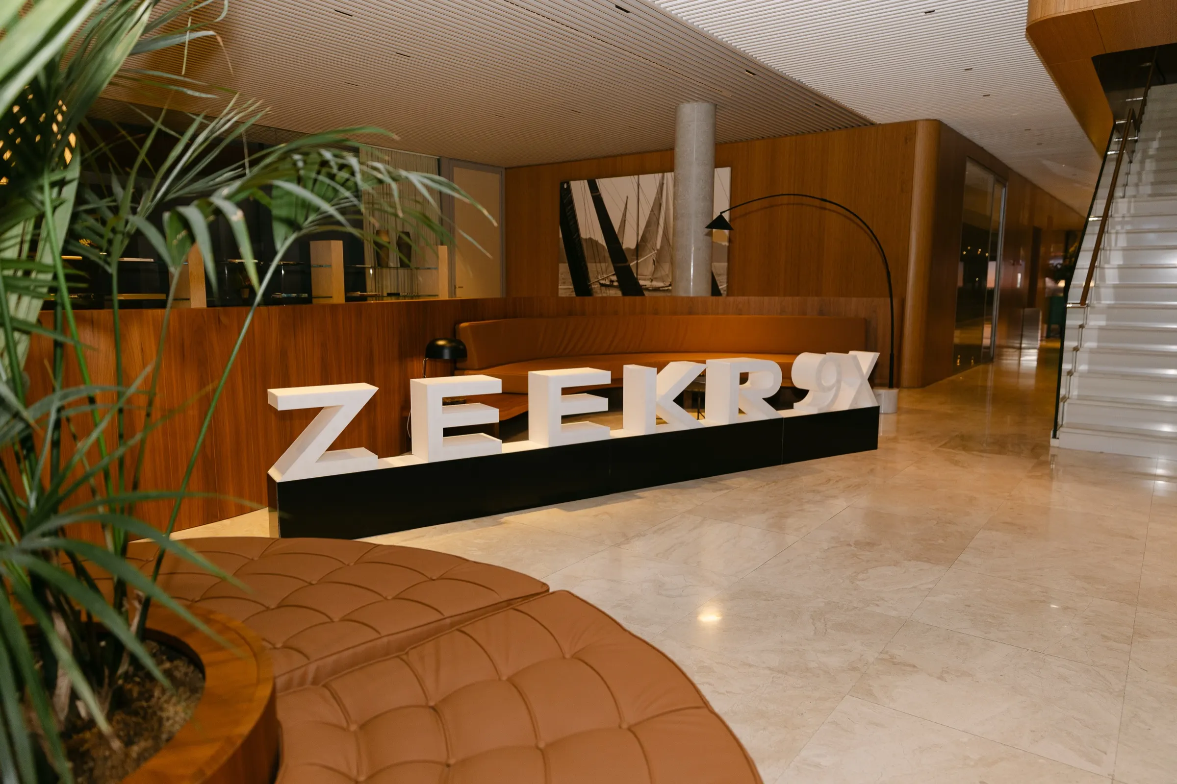 Logotipo del Zeekr 9X en el vestíbulo de The Gallery, con sofá de cuero y plantas. Fotografía de Noomadik.