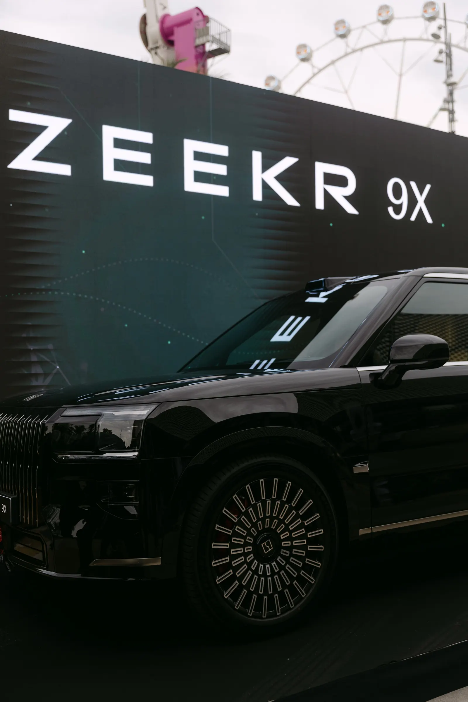 Zeekr 9X negro expuesto ante un panel con la marca en el muelle de Marina Port Vell. Fotografía de Noomadik.