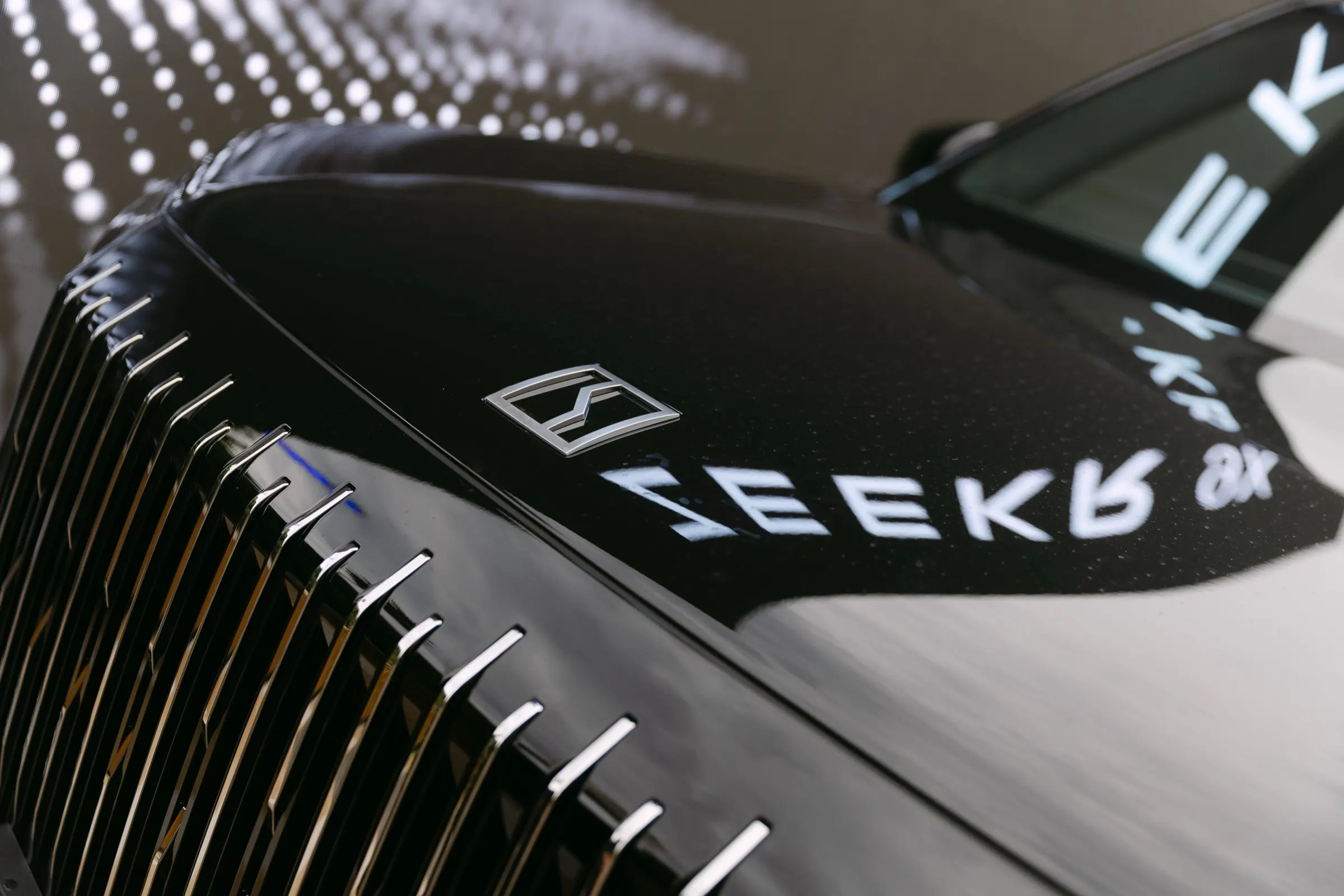 Detalle de la calandra cromada y el logotipo reflejado en el capó del Zeekr 9X. Fotografía de Noomadik.