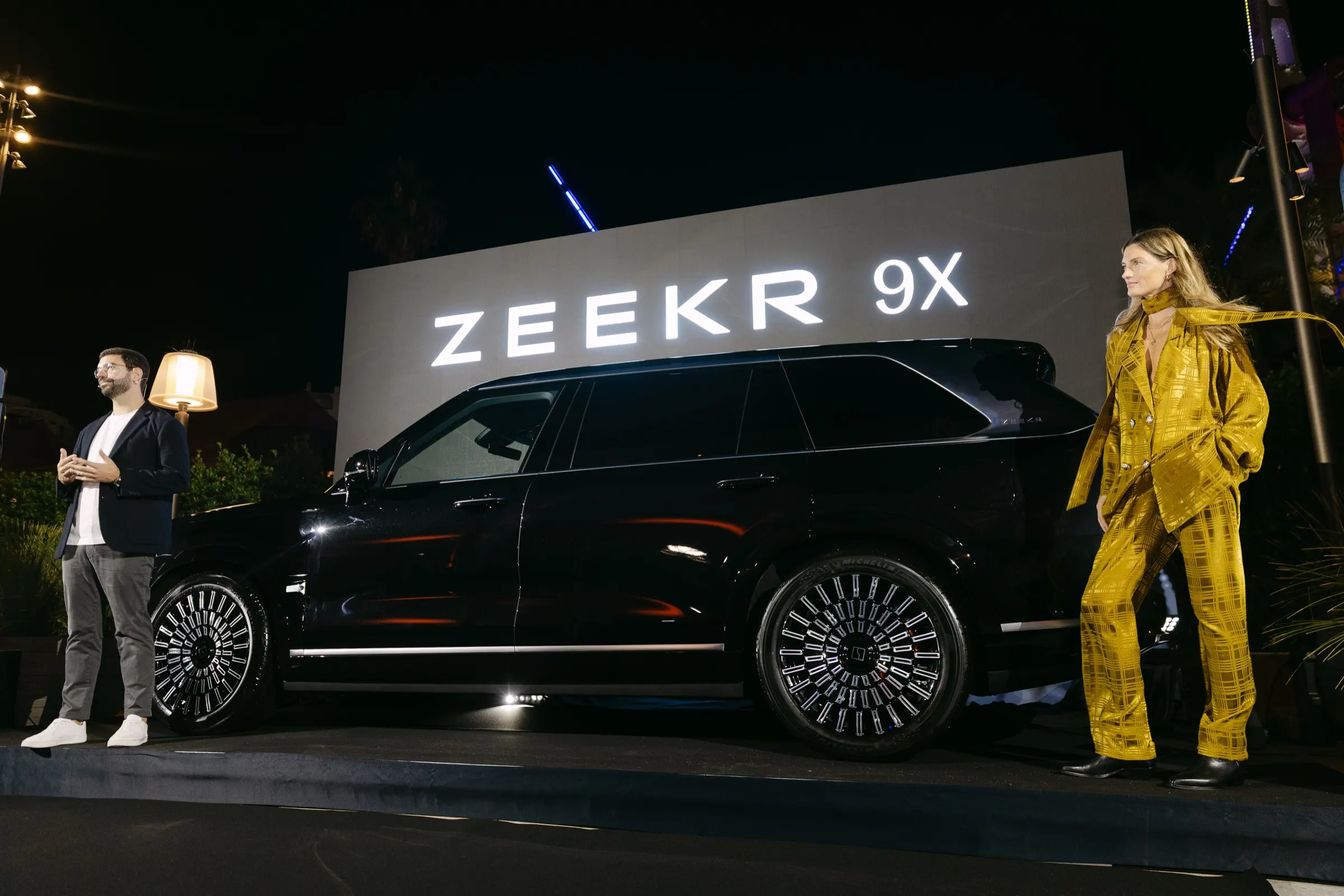 Presentador y modelo junto al Zeekr 9X sobre el escenario durante el desvelado nocturno. Fotografía de Noomadik.